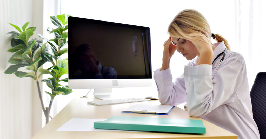 Physician stressed at her desk.